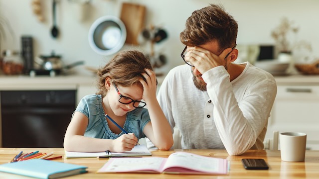 Un homme et une fille assis à une table en train de faire leurs devoirs.