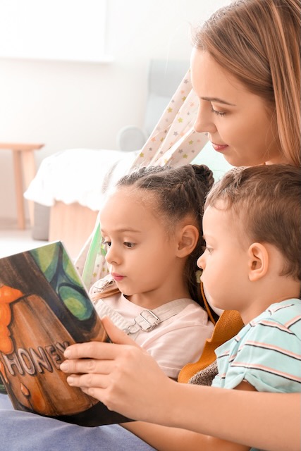 Une femme lit un livre à ses enfants.