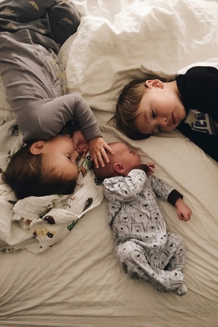 Trois enfants allongés sur un lit avec un bébé qui représente un changement de vie.